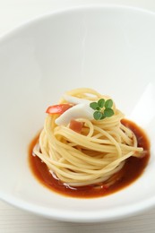 Photo of Tasty spaghetti with sauce on white wooden table, closeup. Exquisite presentation of pasta dish