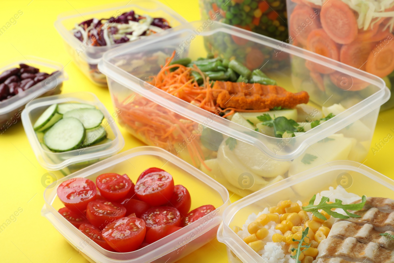 Photo of Set of plastic containers with fresh food on yellow background