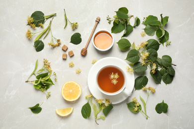 Photo of Flat lay composition with tasty tea and linden blossom on light grey marble table