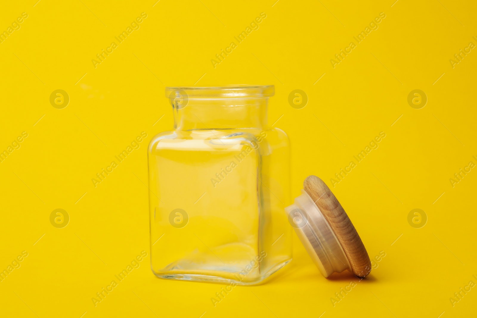 Photo of Open empty glass jar on yellow background