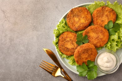 Tasty vegan cutlets served with sauce on light grey table, flat lay. Space for text