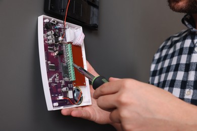 Man installing home security alarm system on gray wall, closeup