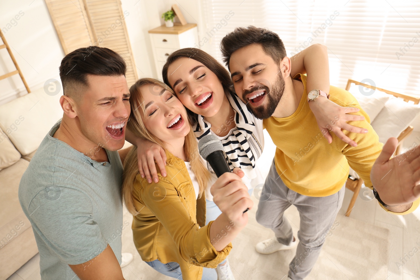 Photo of Happy friends singing karaoke together at home