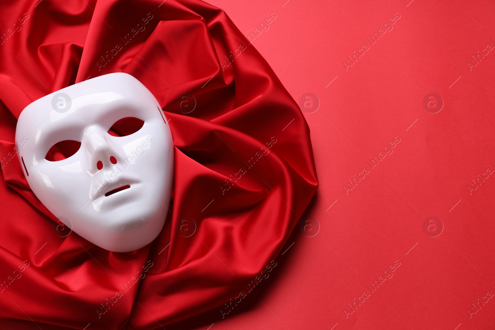Photo of Theater arts. White mask and fabric on red background, above view. Space for text