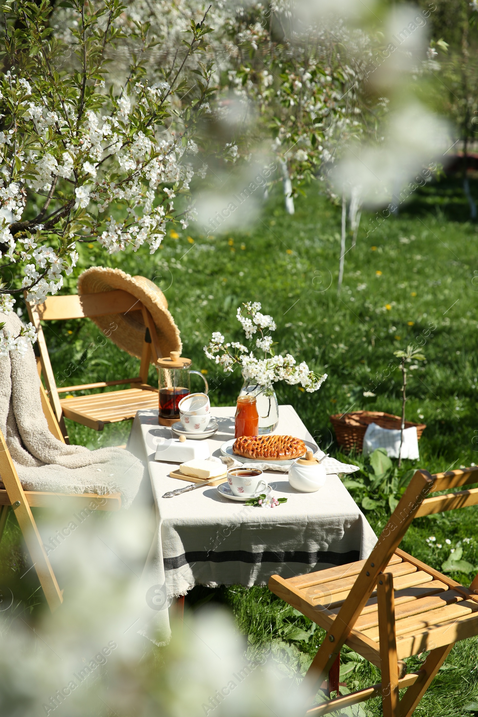 Photo of Beautiful table setting with spring flowers in garden on sunny day