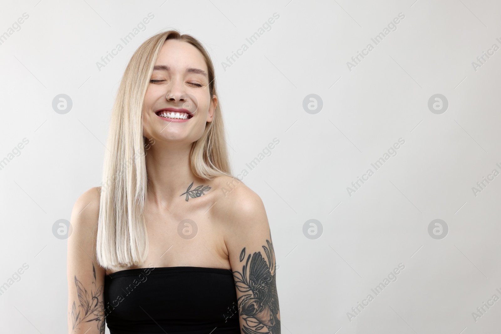 Photo of Portrait of beautiful tattooed woman on light background, space for text