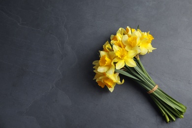 Photo of Bouquet of daffodils on dark background, top view with space for text. Fresh spring flowers