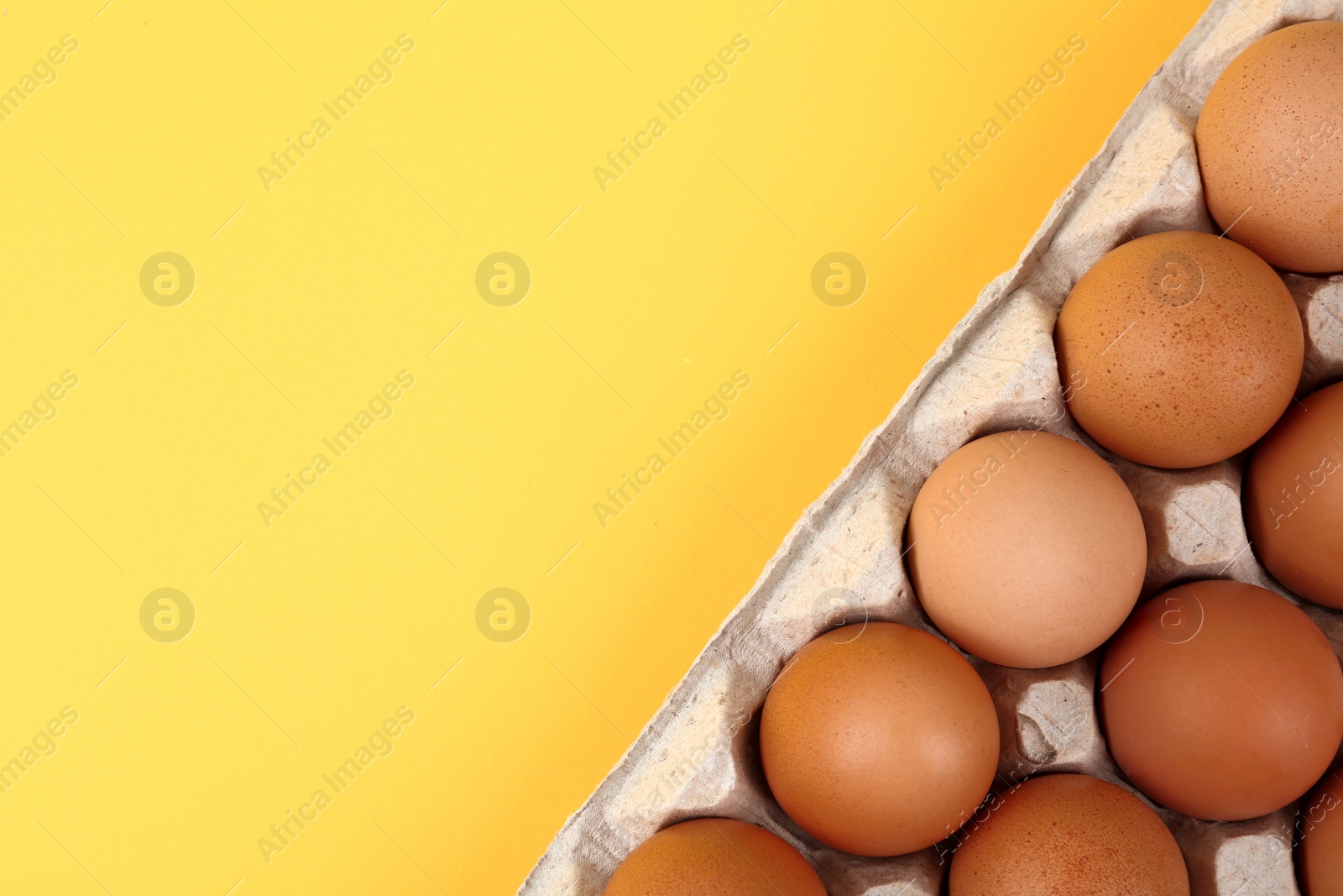 Photo of Raw chicken eggs on yellow background, top view. Space for text