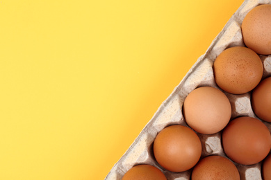 Photo of Raw chicken eggs on yellow background, top view. Space for text