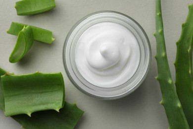 Photo of Jar with cream and cut aloe leaves on light grey background, flat lay