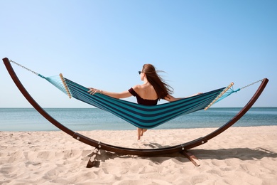 Young woman relaxing in hammock on beach