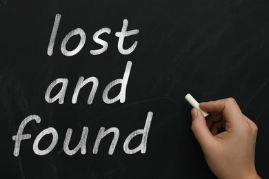 Woman write phrase Lost and Found on blackboard, closeup