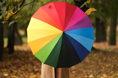 Photo of Woman with rainbow umbrella in autumn park