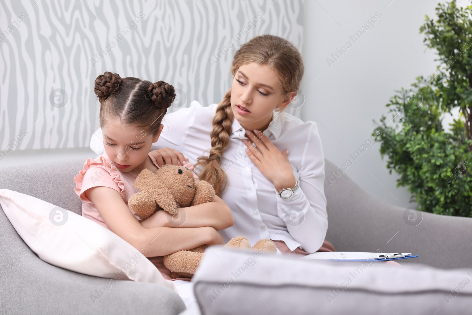 Photo of Young female psychologist working with little child in office