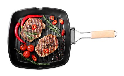Photo of Grill pan with delicious pork steaks, spices and vegetables isolated on white, top view