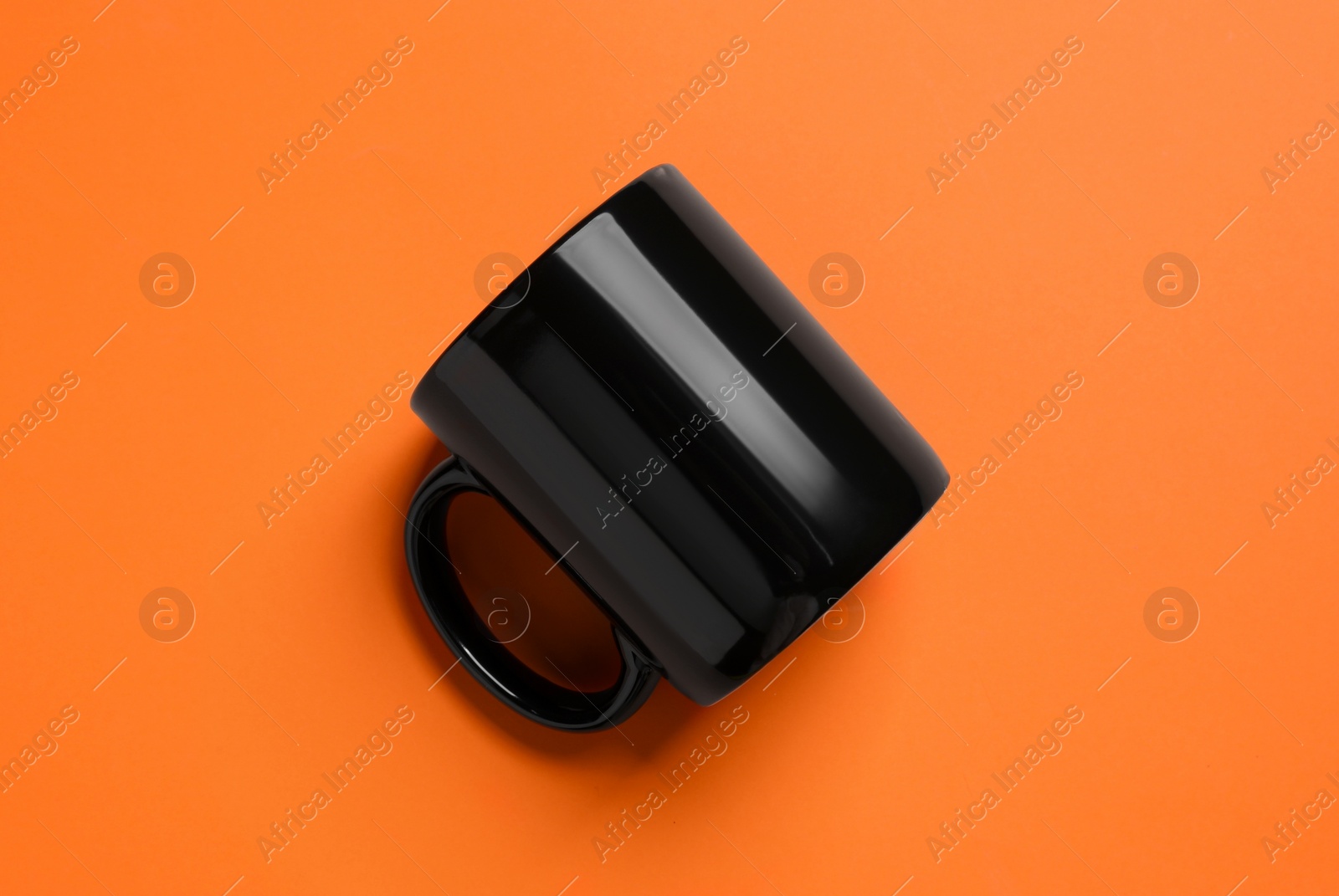 One black ceramic mug on orange background, top view Photo of One black ceramic mug on orange background, top view