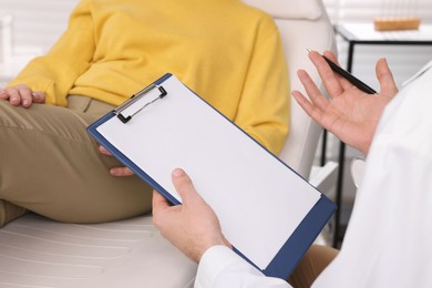 Photo of Doctor with clipboard consulting patient in clinic, closeup