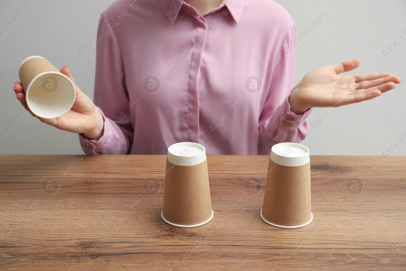 Photo of Woman playing shell game at wooden table, closeup