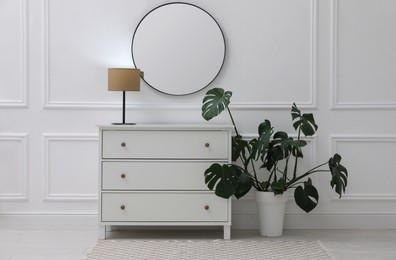 Photo of Light hallway with stylish mirror and chest of drawers. Interior design