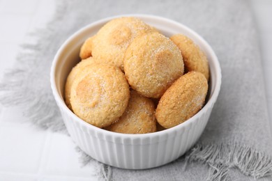 Photo of Tasty sugar cookies in bowl on white tiled table, closeup