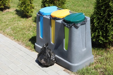 Photo of Plastic bag with garbage and recycling bins outdoors. Waste sorting