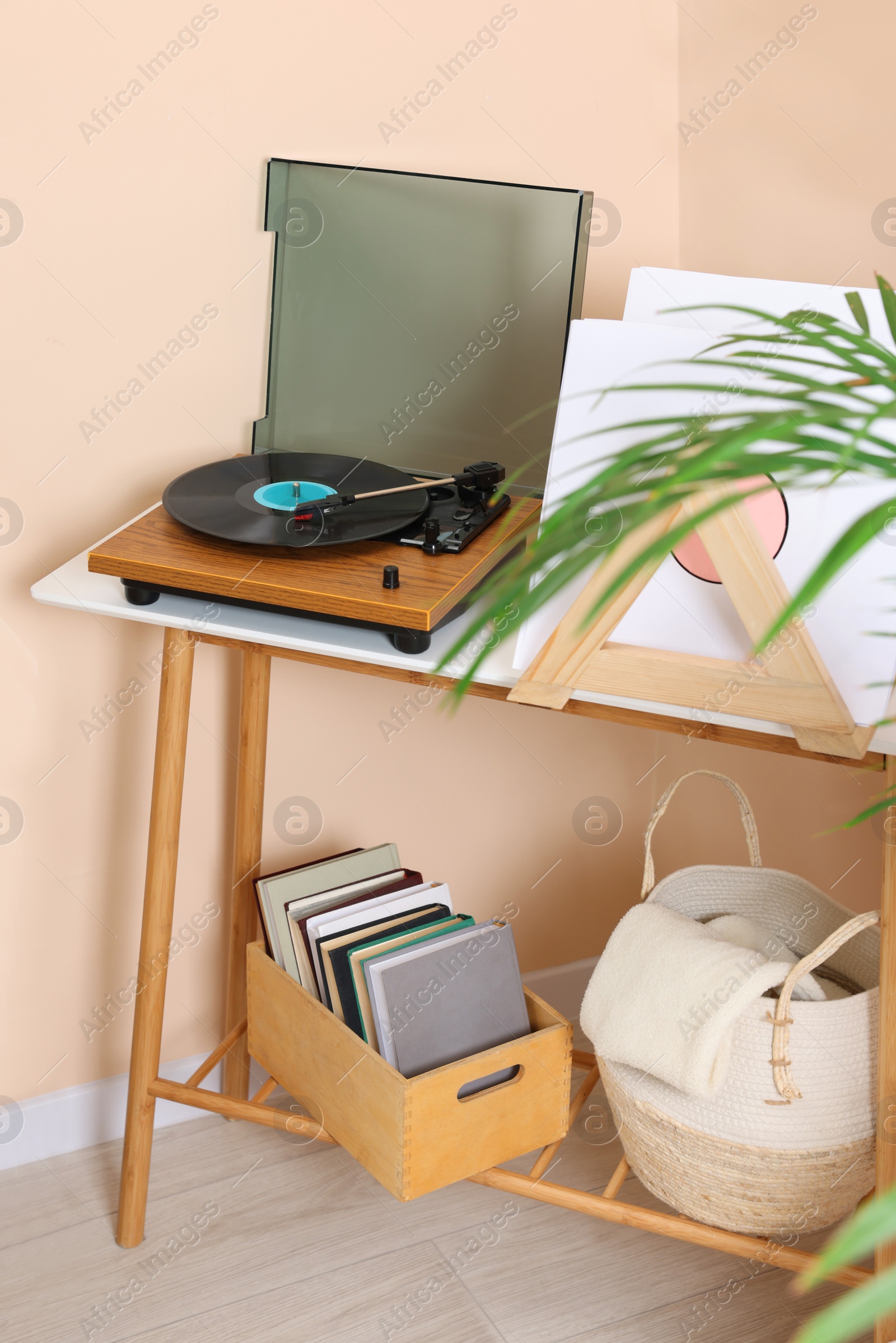 Photo of Stylish turntable with vinyl record on console table in cozy room