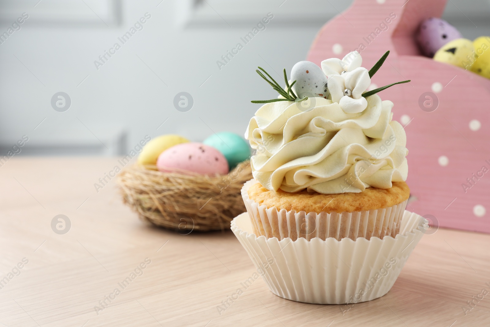 Photo of Tasty Easter cupcake with vanilla cream on wooden table, space for text