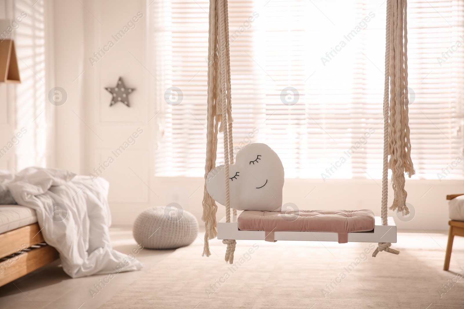 Photo of Beautiful swing with toy heart in bedroom. Stylish interior design