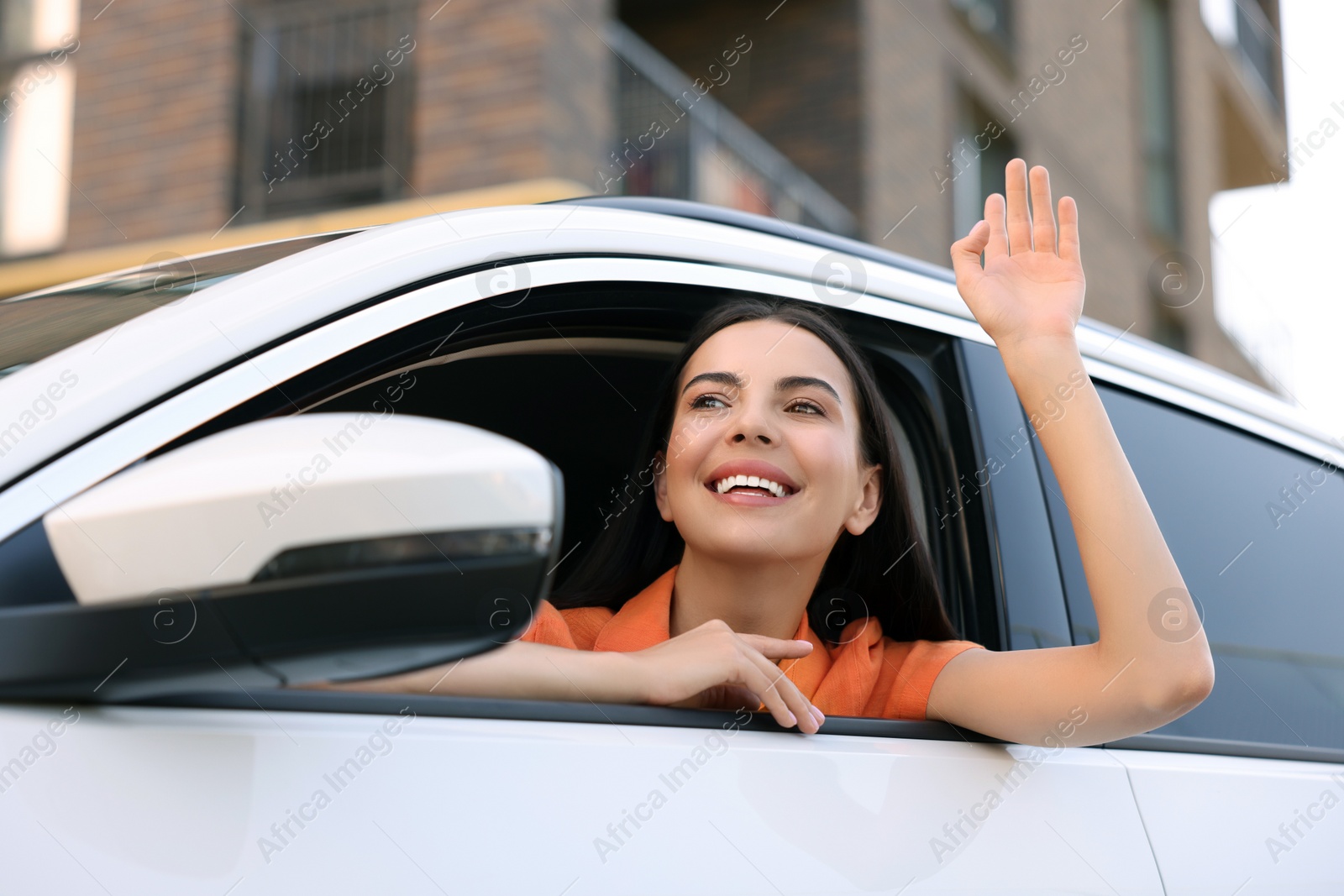 Photo of Happy young woman looking out of car window on city street, view from outside. Enjoying trip