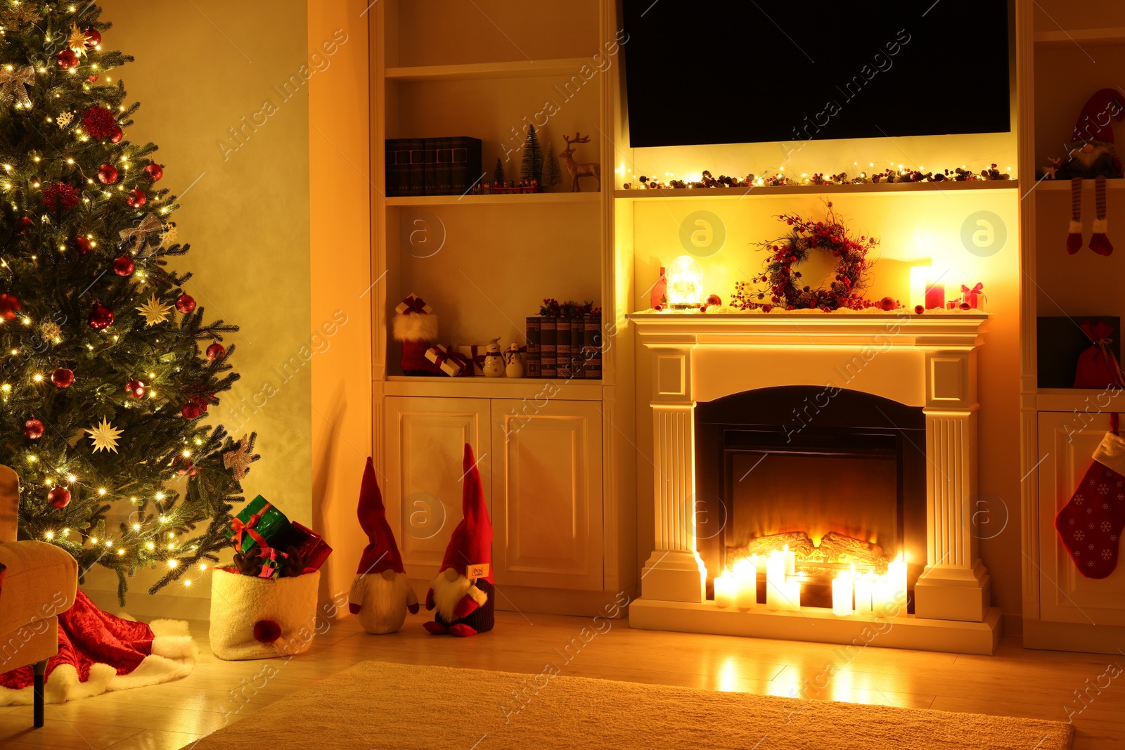 Photo of Cosy room with fireplace and burning candles in evening. Christmas atmosphere