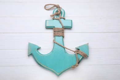 Photo of Anchor with hemp rope on white wooden table, top view