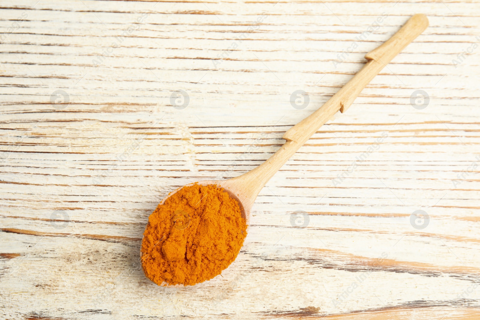 Photo of Spoon with saffron powder on white wooden table, top view
