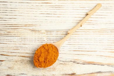 Spoon with saffron powder on white wooden table, top view