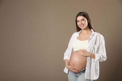 Happy pregnant woman near dark wall, space for text. Baby shower party