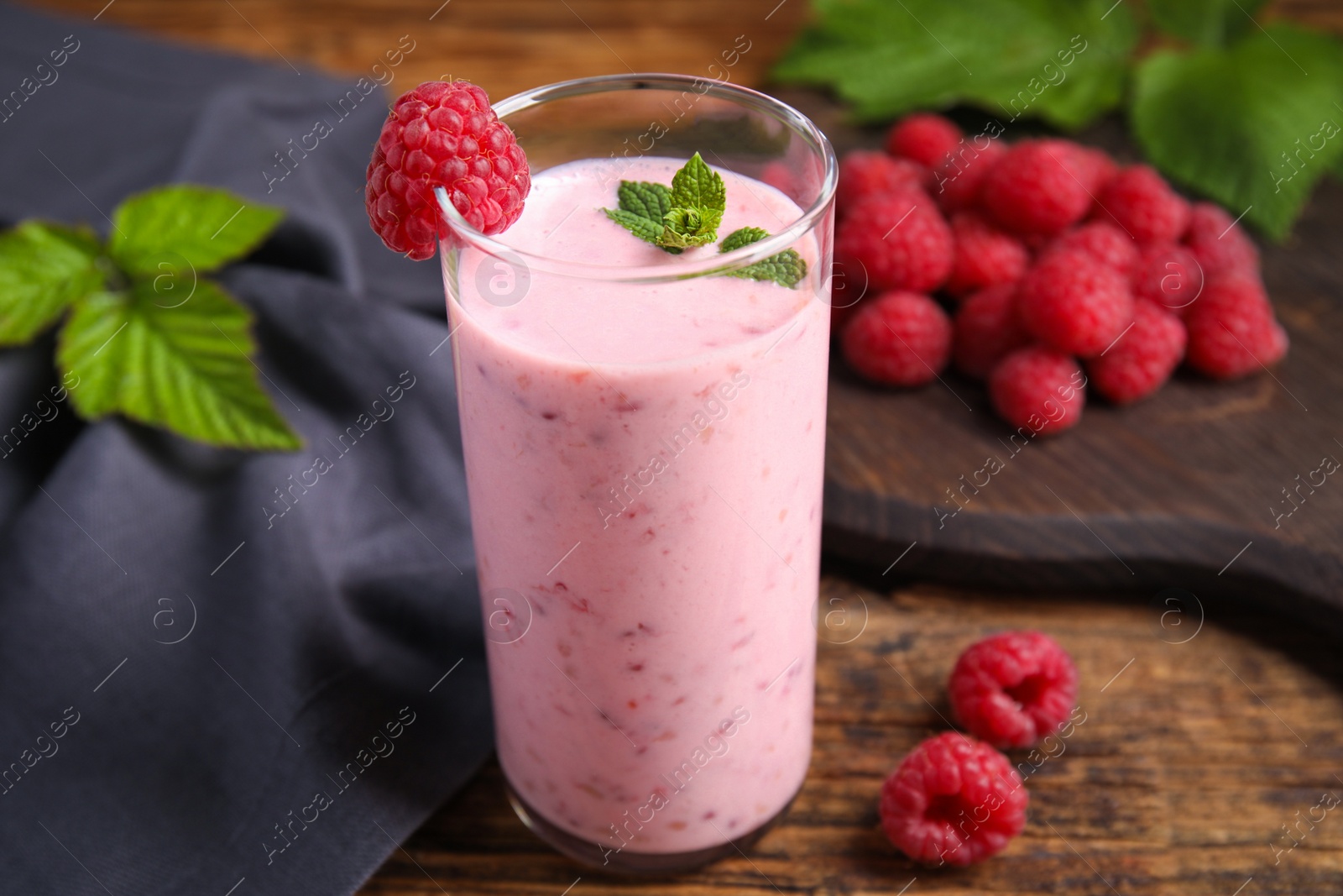 Photo of Glass of tasty fresh raspberry smoothie on wooden table