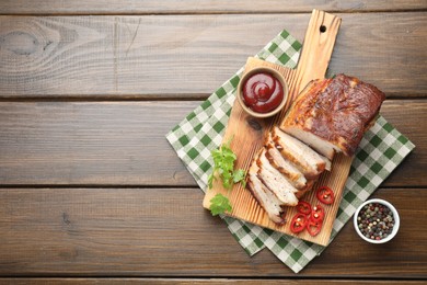 Photo of Pieces of baked pork belly served with sauce, chili pepper and parsley on wooden table, top view. Space for text