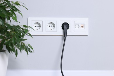 Power sockets and electric plug on grey wall