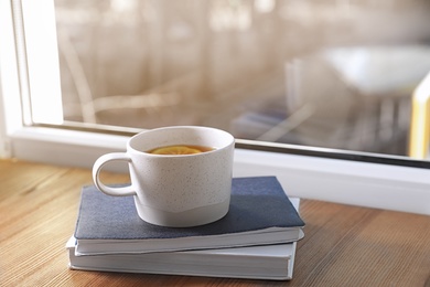 Photo of Cup of winter drink and books on windowsill. Space for text