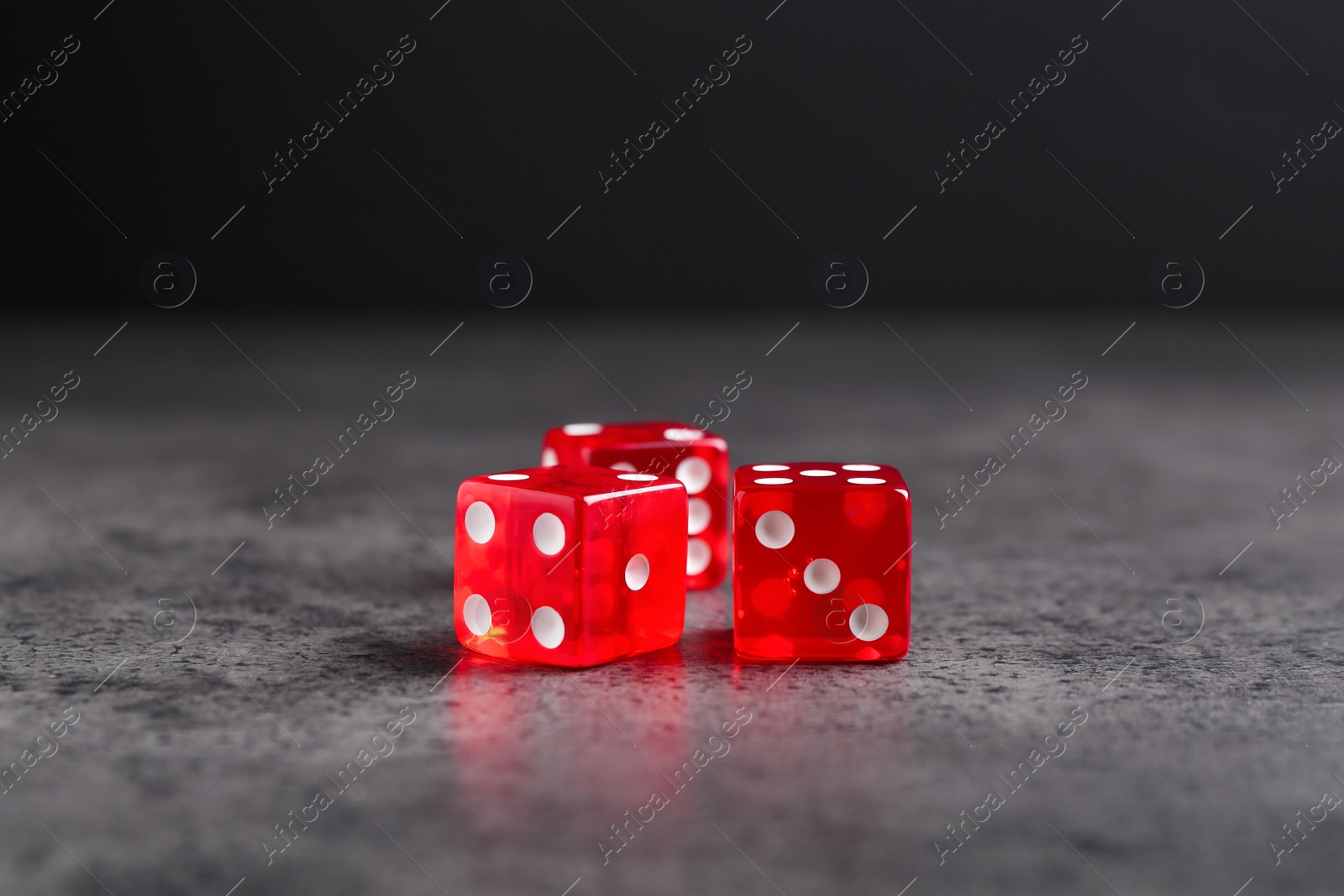 Photo of Three red game dices on grey textured table