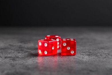 Photo of Three red game dices on grey textured table