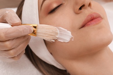 Photo of Young woman during face peeling procedure in salon, closeup