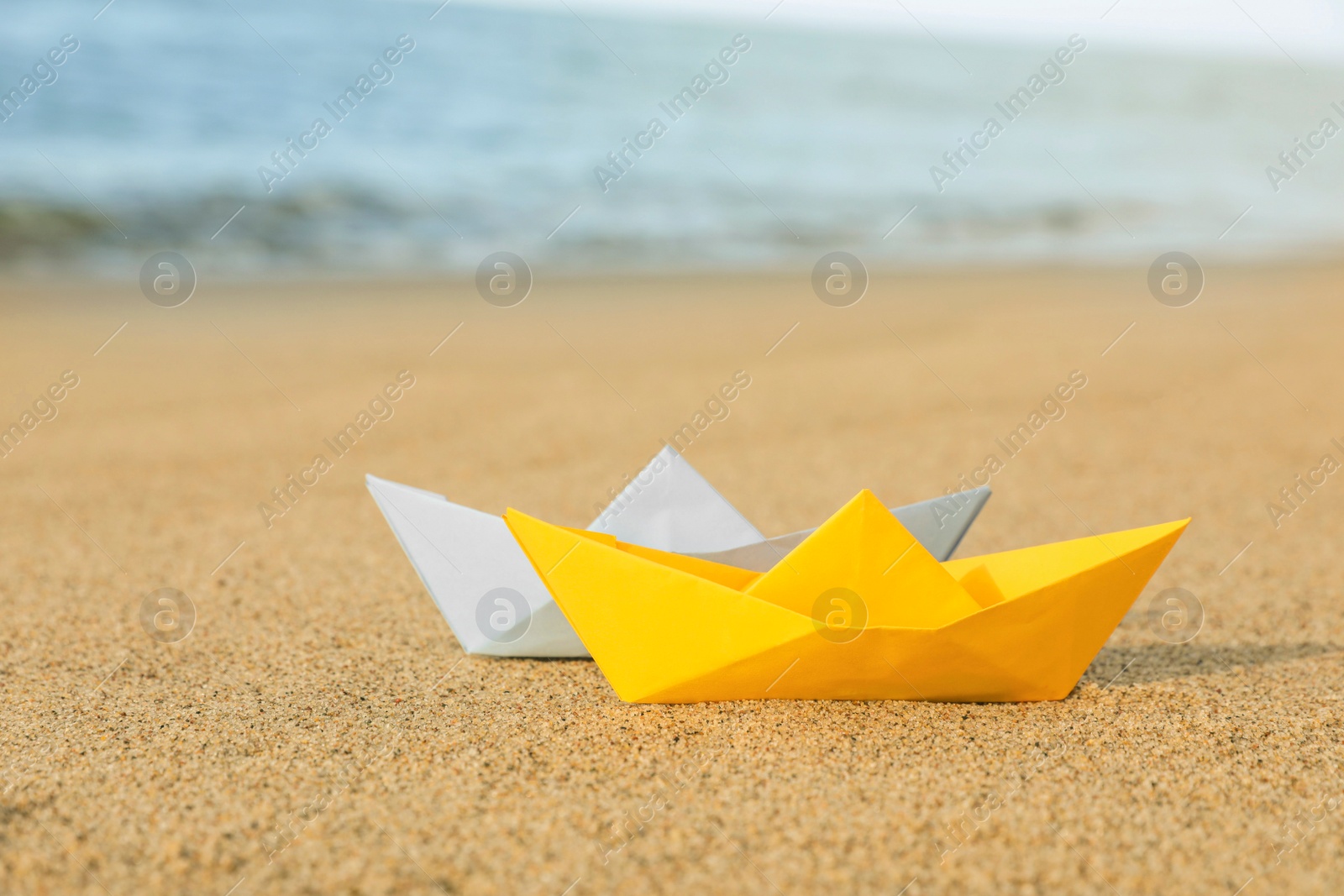 Photo of Color paper boats near sea on sandy beach