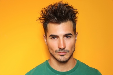 Photo of Young man with trendy hairstyle posing on color background