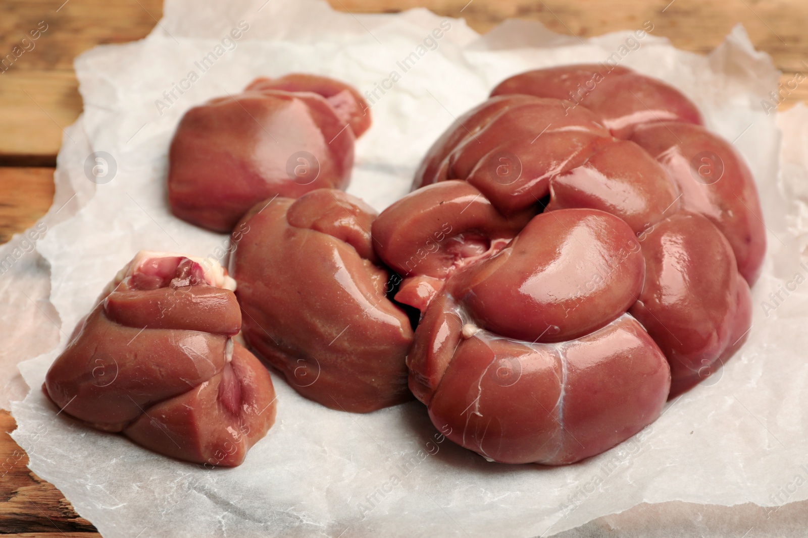 Photo of Fresh raw kidneys on parchment paper, closeup