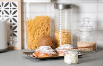 Photo of Jar with coconut oil and tasty pastry on table in kitchen. Healthy cooking