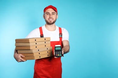 Photo of Smiling courier with pizza boxes and payment terminal on color background. Space for text