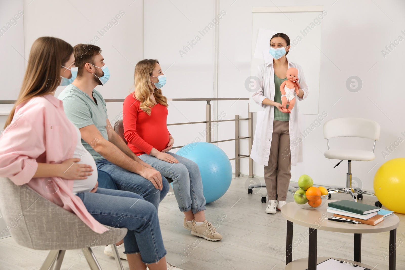 Photo of Pregnant women, man and doctor with protective masks at courses for expectant parents indoors