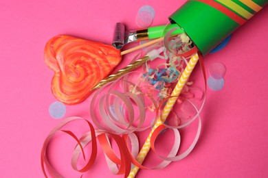 Photo of Party cracker and different festive items on bright pink background, flat lay