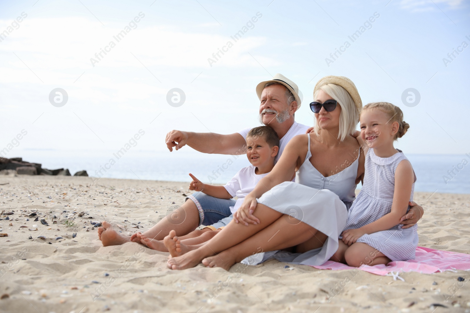 Photo of Cute little children with grandparents spending time together on sea beach