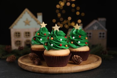 Photo of Christmas tree shaped cupcakes on black table